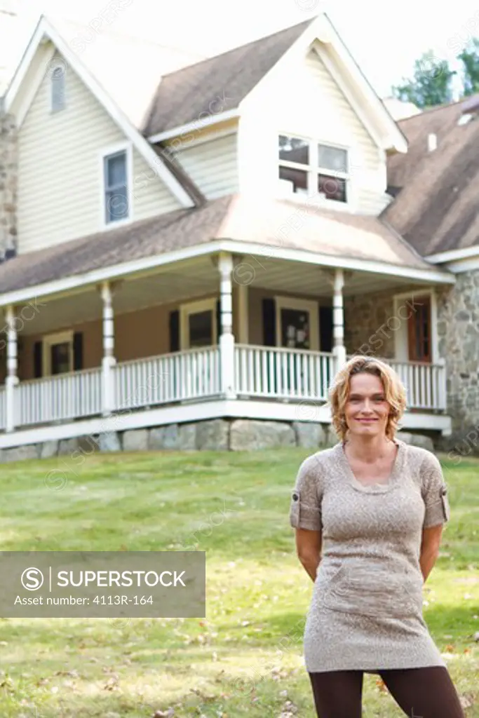 Portrait of smiling woman standing in front of large house