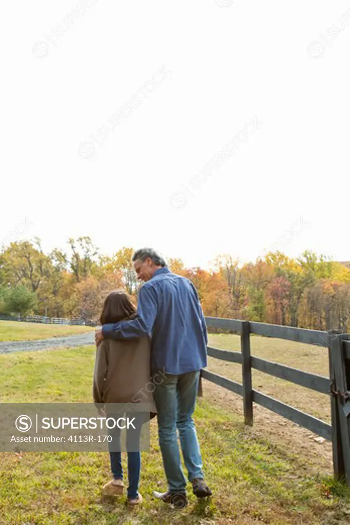 Rear view of father and daughter walking on field