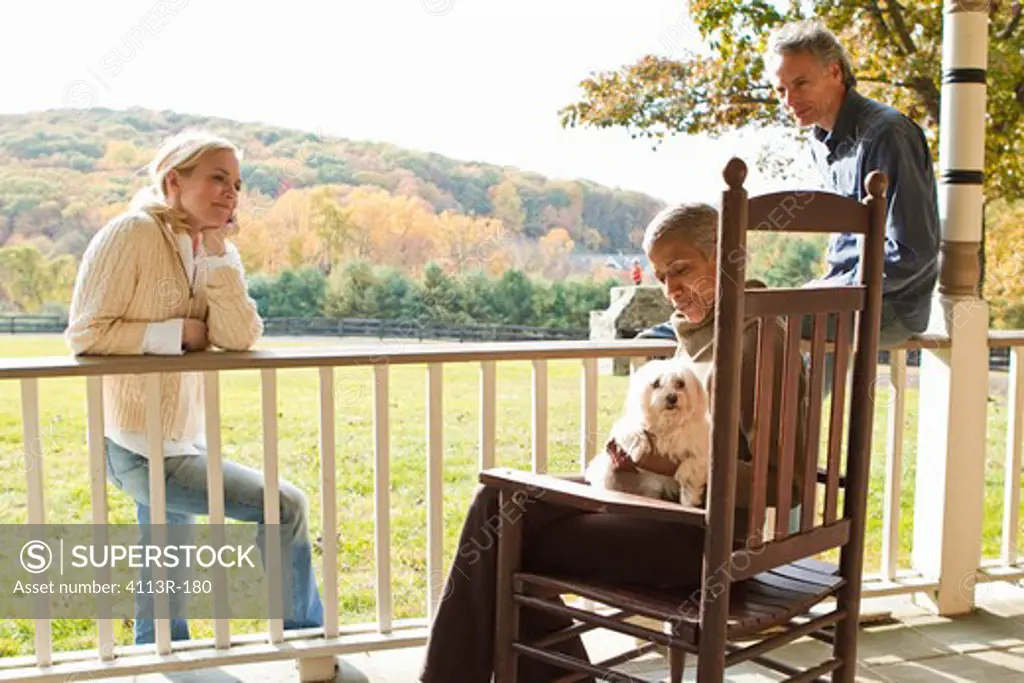 People with dog relaxing on porch in rural landscape