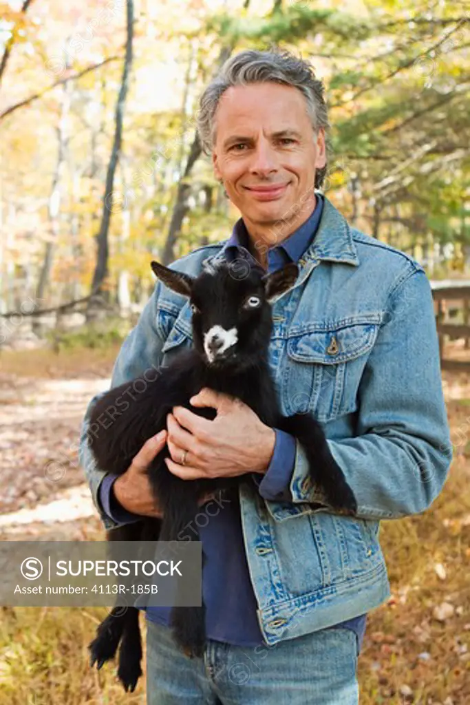 Portrait of farmer holding black lamb