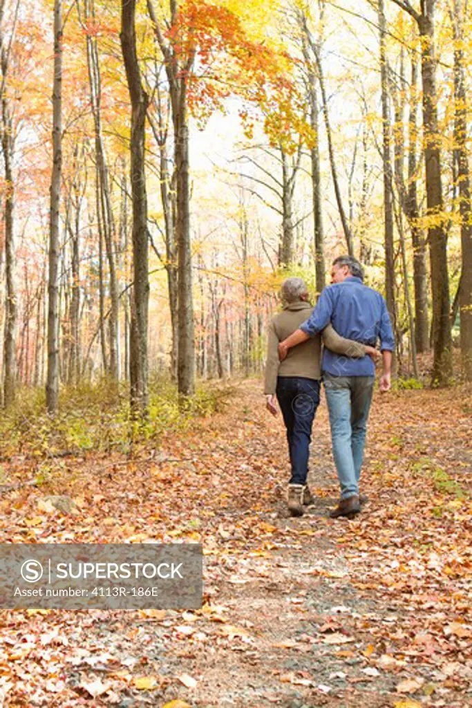 Rear view of mature couple walking on Autumn forest track