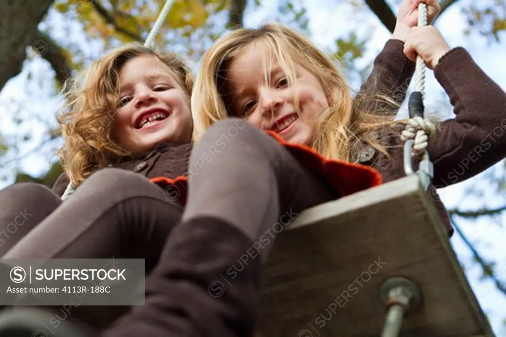 Portrait of two girls on swing