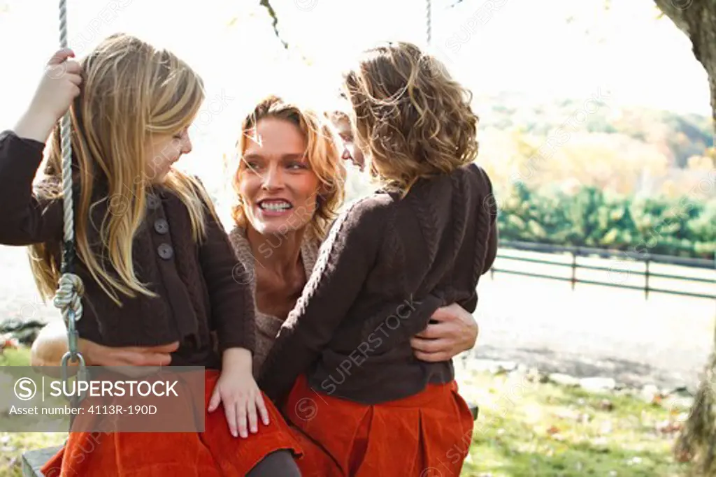 Mother with two daughters on swing
