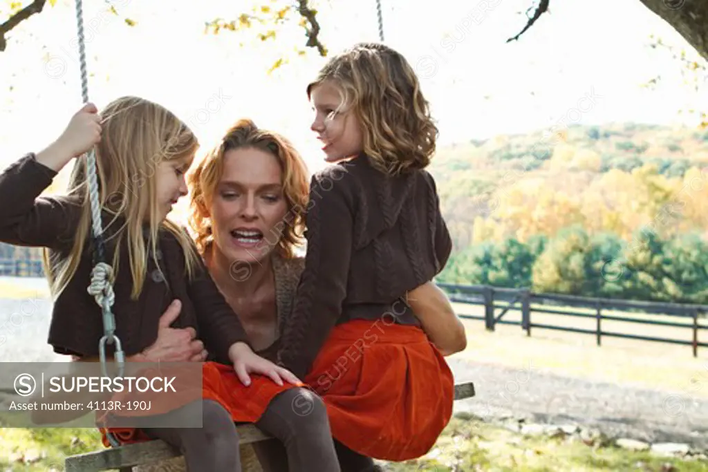 Mother with two daughters on swing