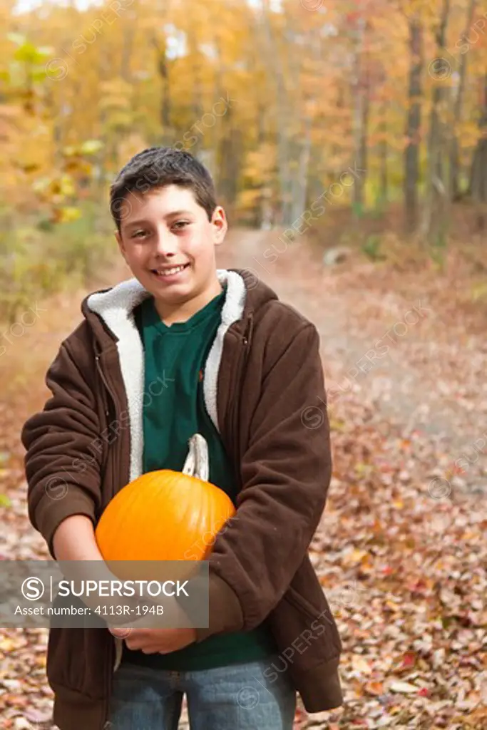 Portrait of boy carrying pumpkin in forest