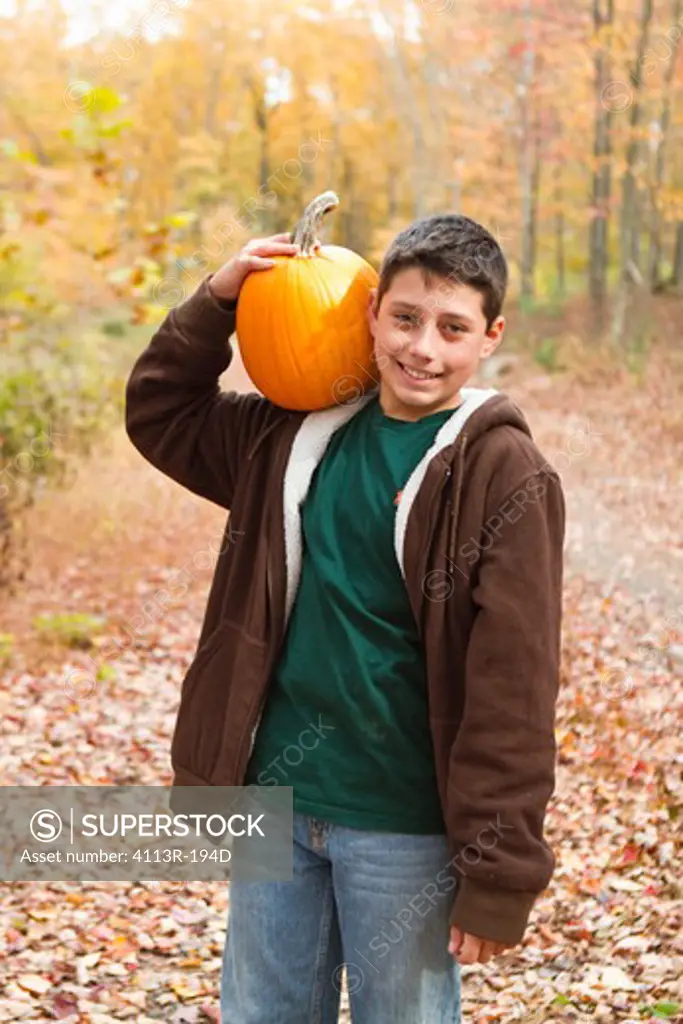 Portrait of boy carrying pumpkin in forest