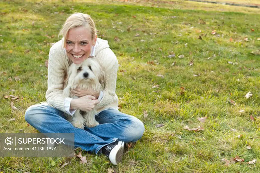 Portrait of woman with white dog sitting on field