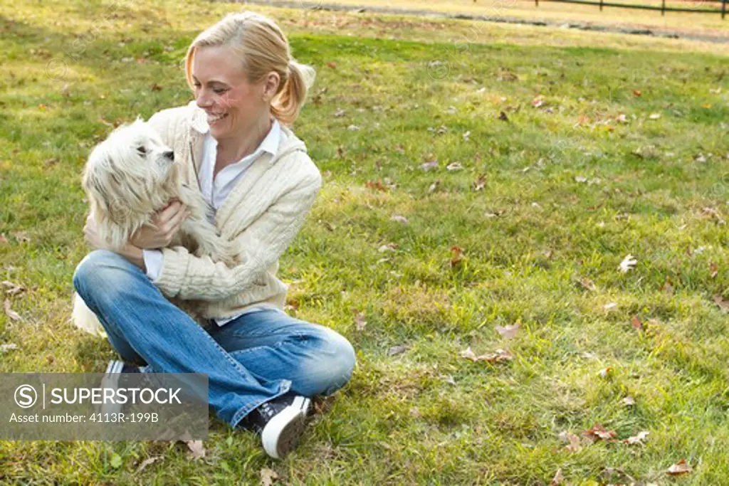 Woman with white dog sitting on field