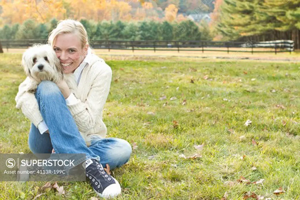 Portrait of woman with white dog sitting on field