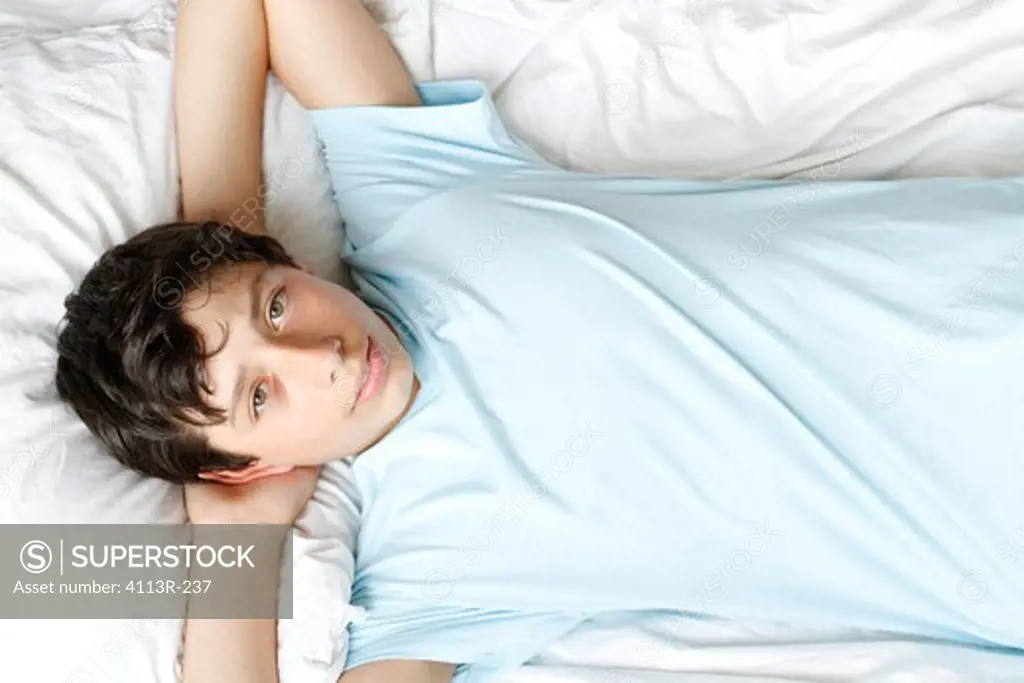 USA, New York City, Manhattan, Portrait of boy lying on bed