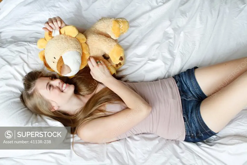 USA, New York City, Manhattan, Young woman lying on bed with toy