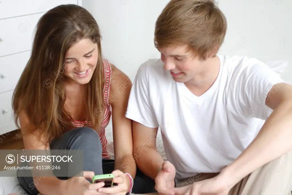 USA, New York City, Manhattan, Couple sitting on bed and texting