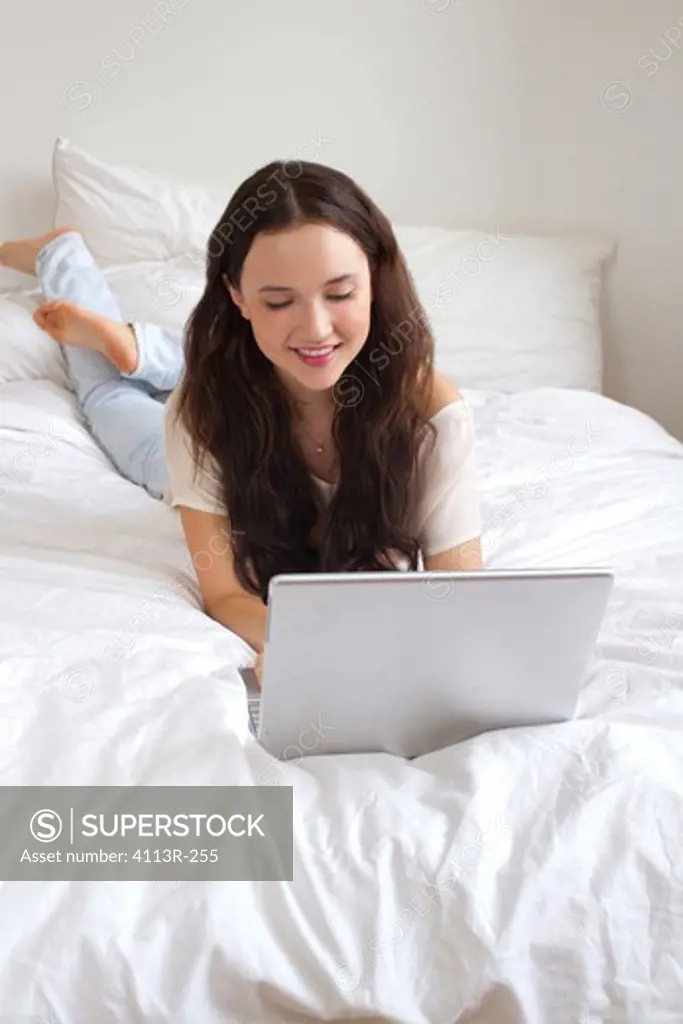 USA, New York City, Manhattan, Girl lying on bed using laptop