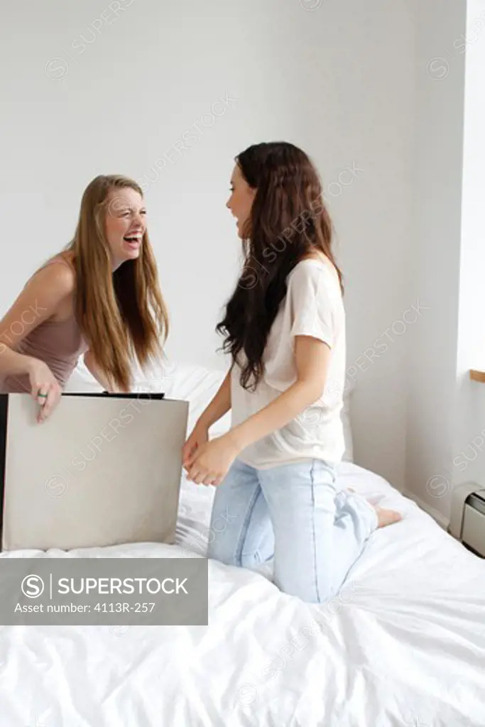 Two girls with shopping bag on bed