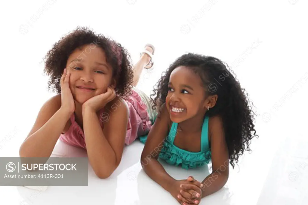 Studio shot of two girls lying on front and talking