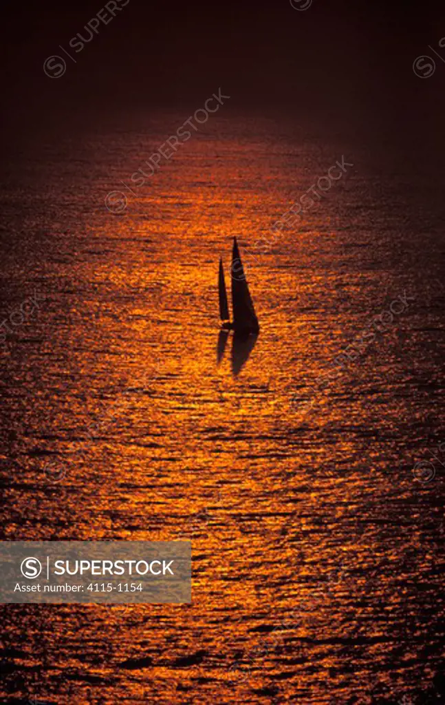 82ft ketch 'Fisher and Paykel' sailing at sunset.