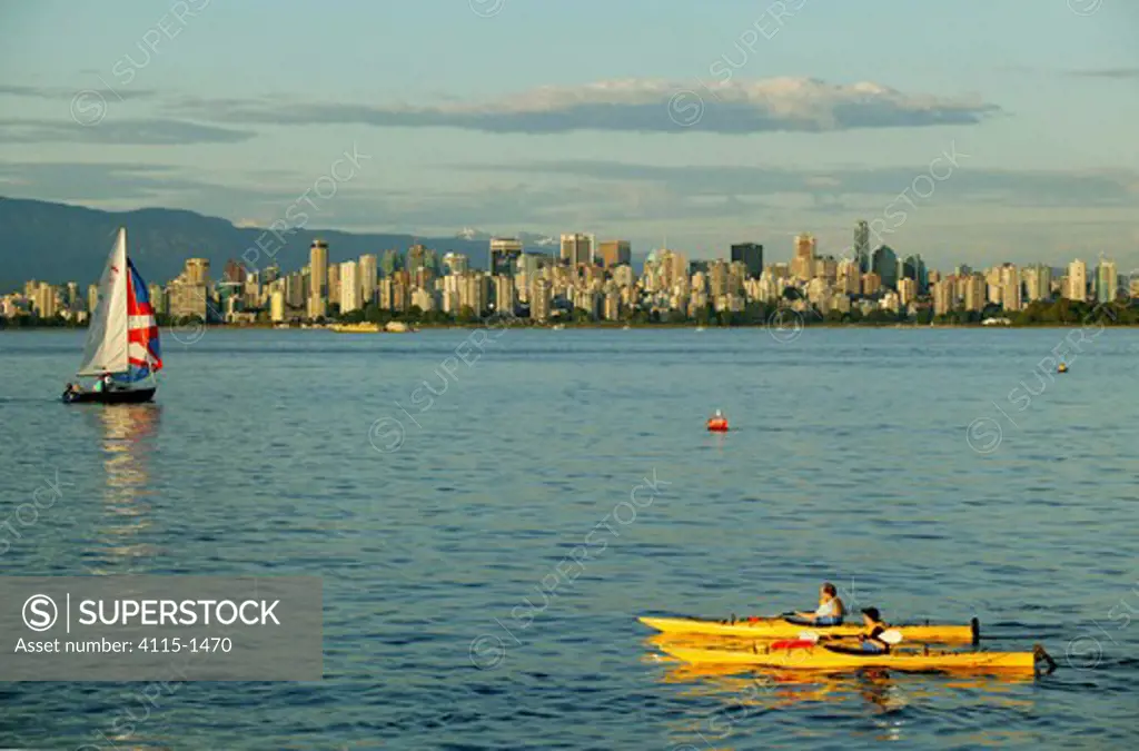 Pair of kayakers paddling in Vancouver with the cityscape beyond, Canada.