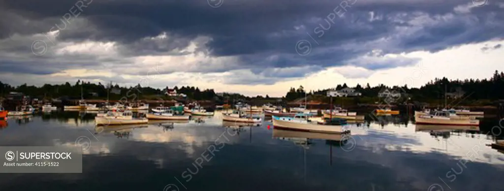Heavy grey clouds reflecting around the boats moored in the harbour, Maine, USA.