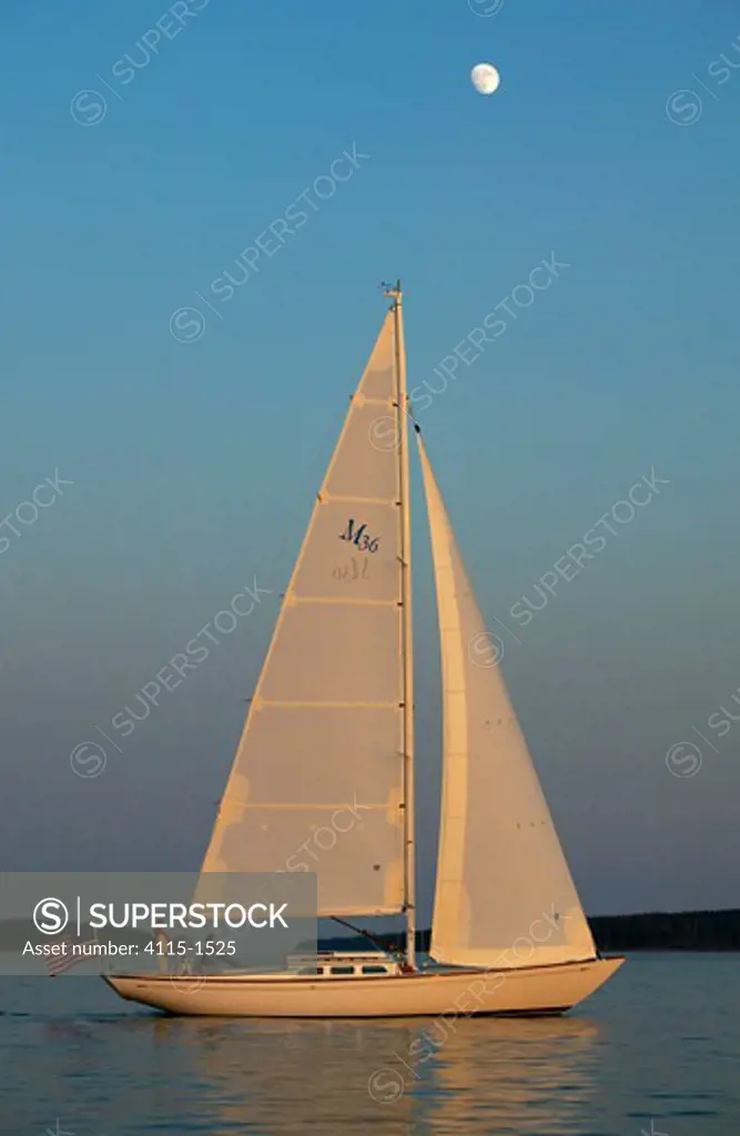 A Sparkman & Stephens designed Morris 36 sailing under the late afternoon sun wih a full moon high above, Maine, USA