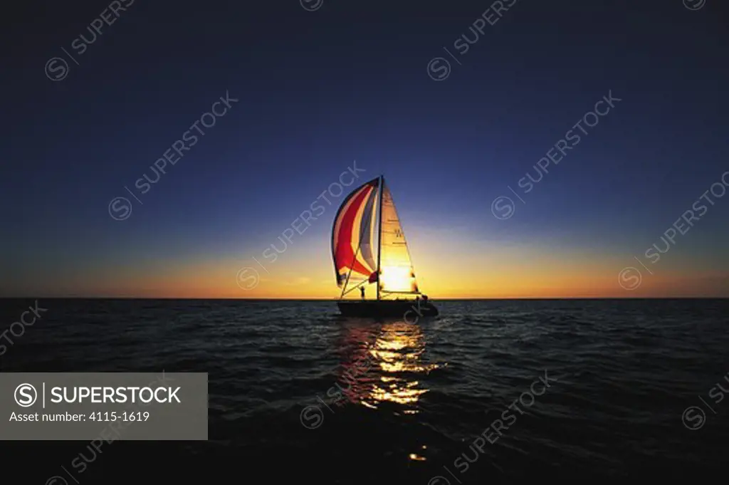 Gybing the spinnaker at sunset on one of the great lakes, USA.
