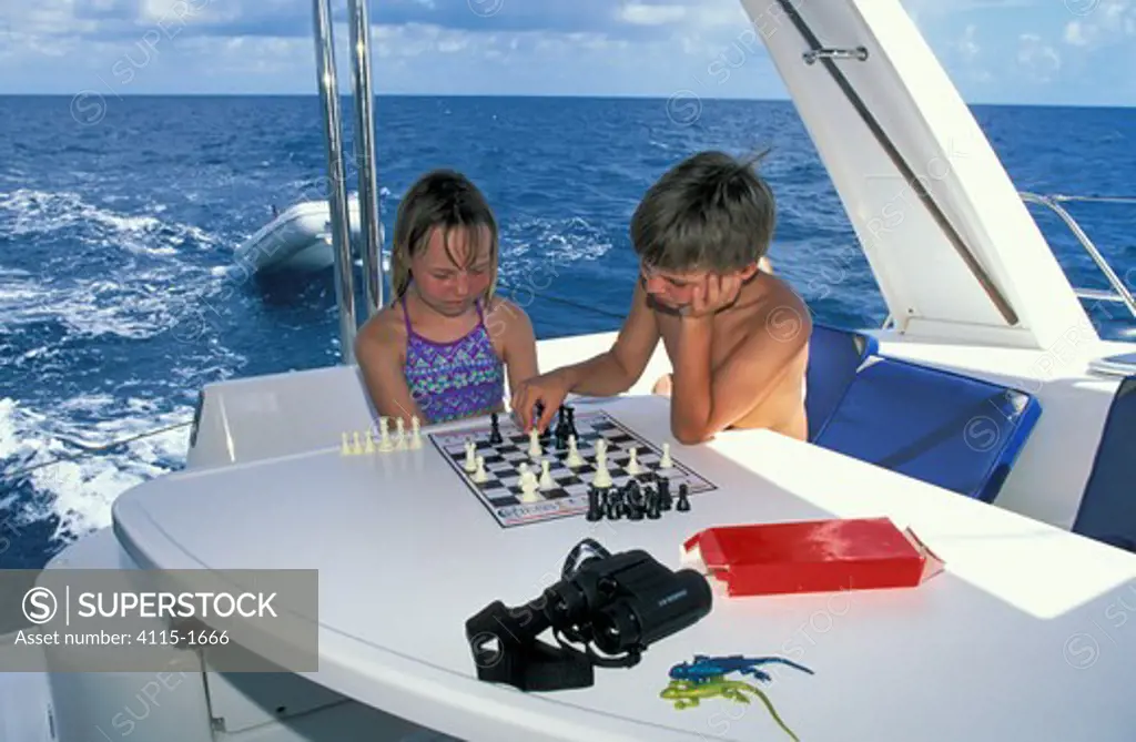 Children playing chess on board a boat.