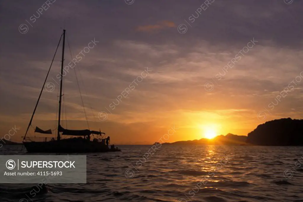 Silhouette of a cruising yacht anchored at sunset.