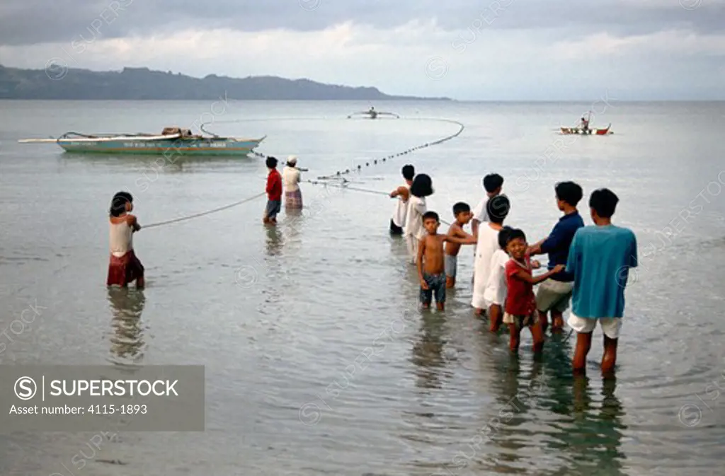 Fishermen, assisted by the whole community, to pull their nets ashore on Dakak Island, Philippines.