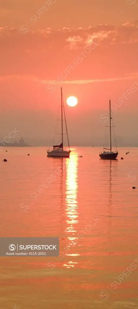 Orange sunrise over two sailboats in Jamestown Harbour, Jamestown, Rhode Island, USA.