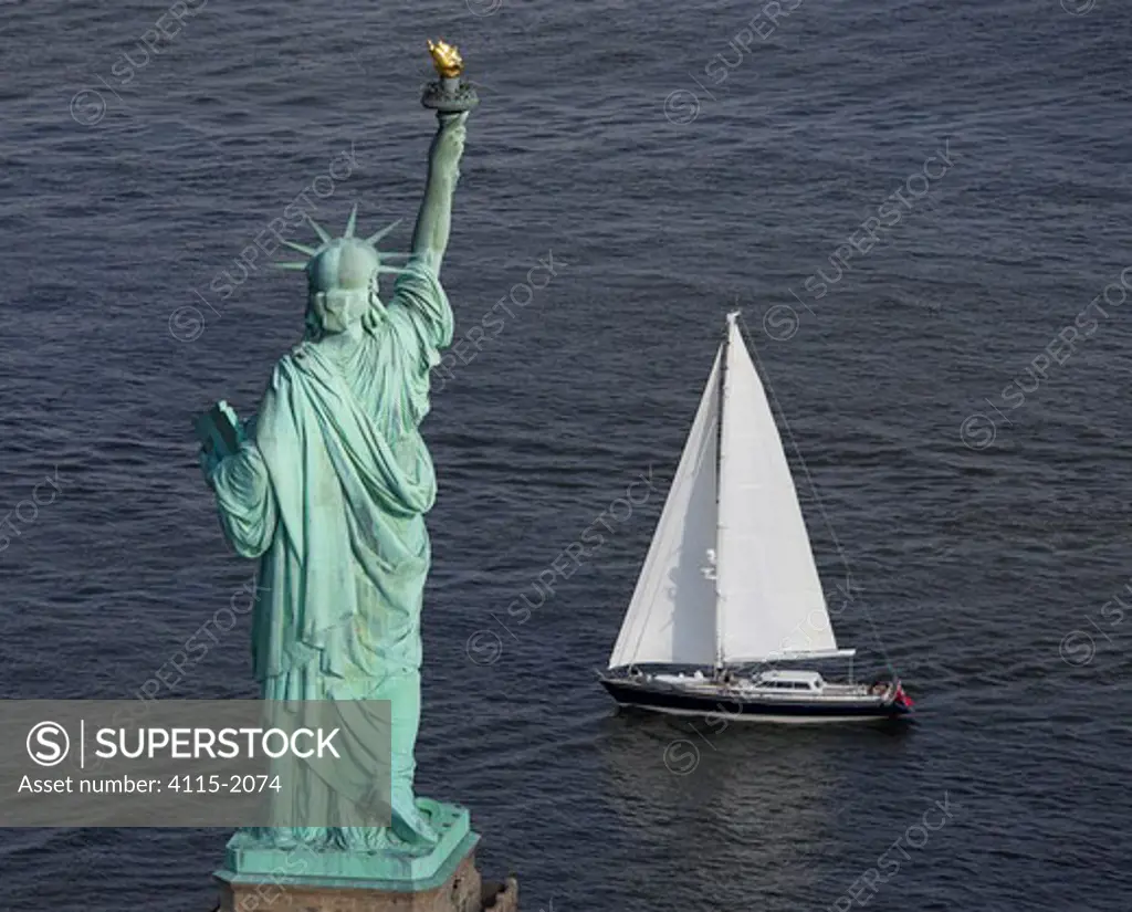 Rear view of the Statue of Liberty with a sailing boat in front, New York harbour, USA.
