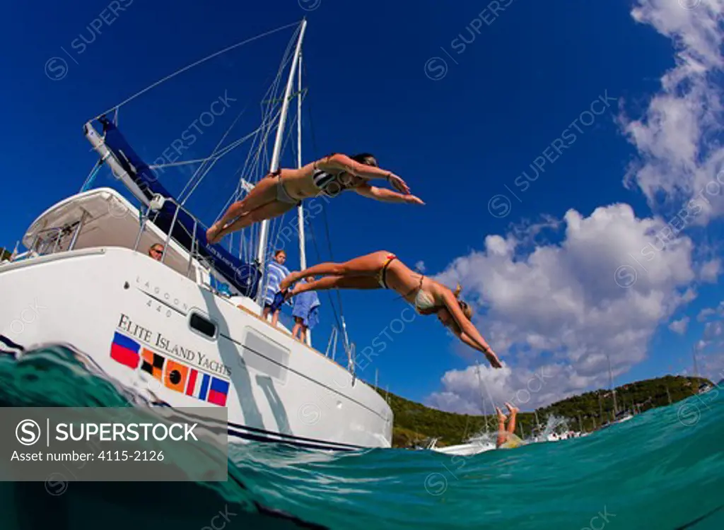 Two girls diving from a catamaran into the sea, British Virgin Islands, Caribbean, December, 2006