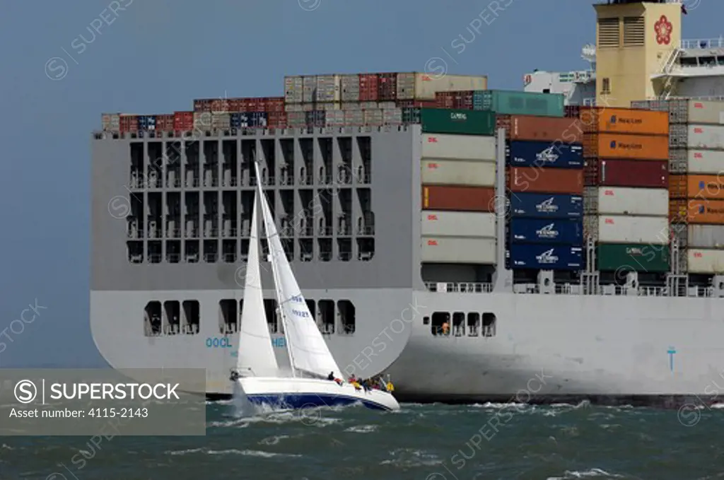 Yacht 'Bounder' passes close to the stern of a container ship in the Solent, UK.
