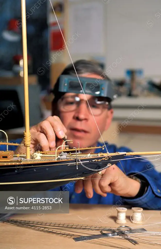 Model boat builder, Robert Eddy, adding detail to a scale model of the 1915 Herreshoff schooner 'Mariette' in his shop in Camden, Maine, USA.