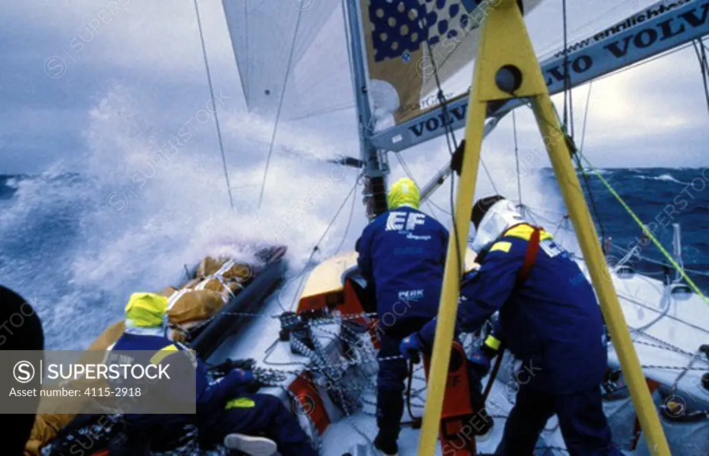 Wave rushes through the crew on deck of 'Team EF' in the Whitbread Round the World Race, 1997-1998.