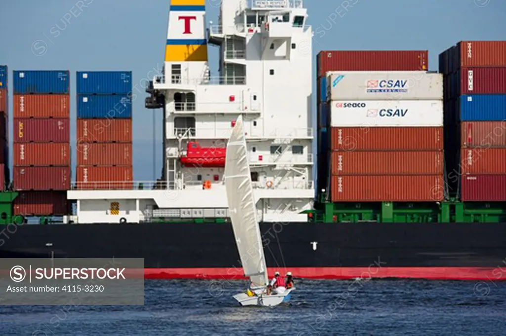 Vanguard Laser dinghy sailing in front of a container ship, Charleston, South Carolina, USA.