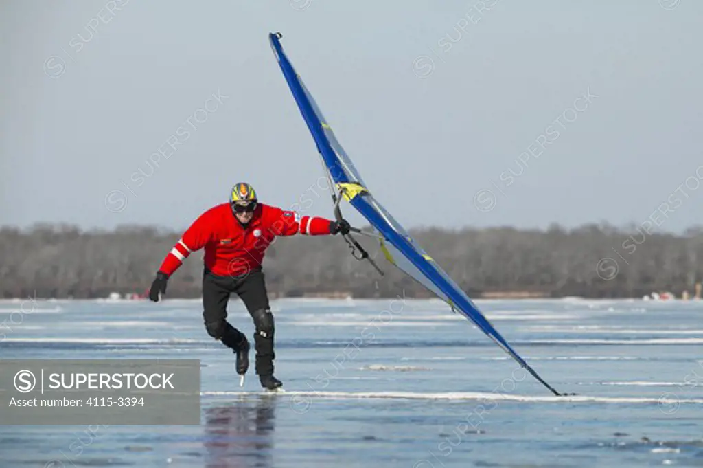 Man ice skating with a sail on Worden Pond, Rhode Island, USA.
