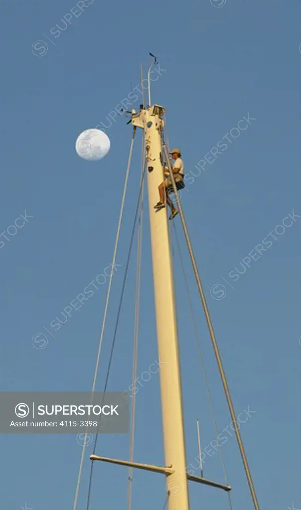 A crew member of a superyacht being hoisted to the masthead under a full moon, St Barts Bucket, Caribbean.