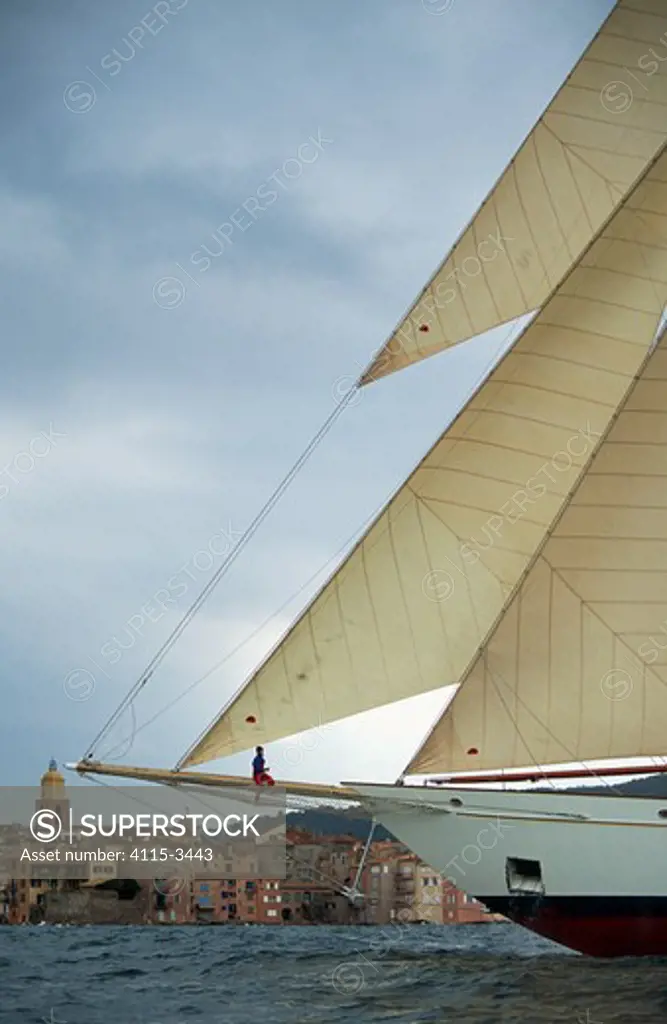 A crew member sitting on the bowsprit of classic wooden boat 'Adix' during the Nioulargue sailing festival, St Tropez, France. Property Released.