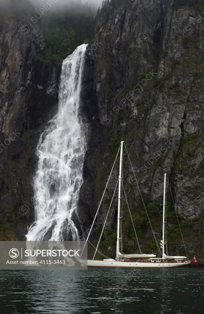 180ft Superyacht 'Adele' exploring the Norwegian Fjords in the Sognefjorde area, during week 25 of her maiden voyage. A waterfall forms a dramatic backdrop.