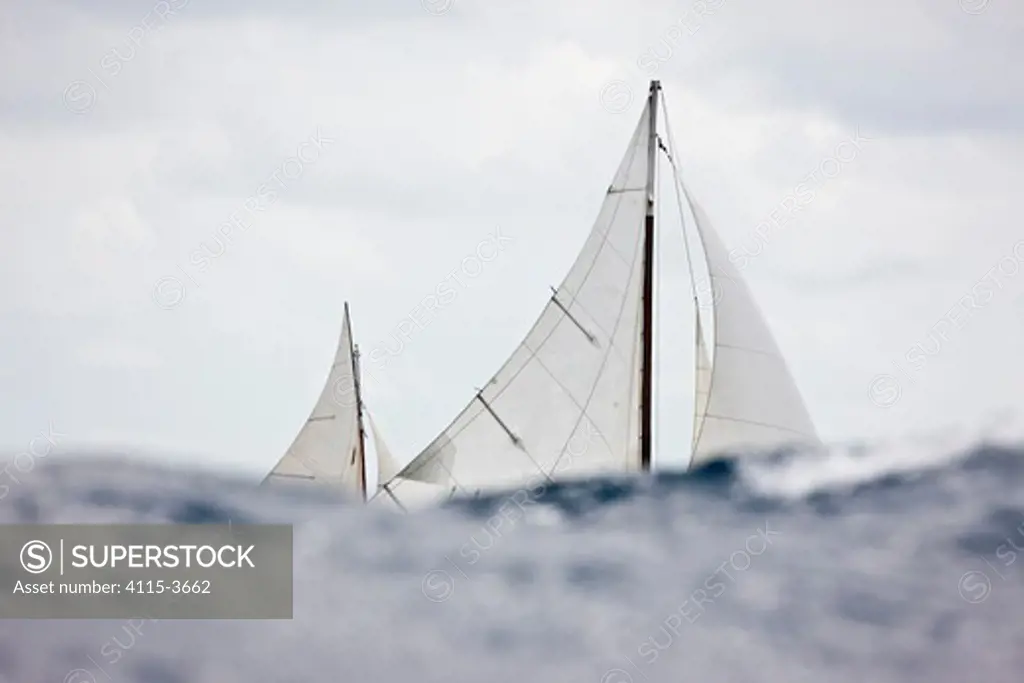 Sails of a classic yacht visible over the crests of waves, Panerai Antigua Classic Yacht Regatta, Caribbean, April 2010.