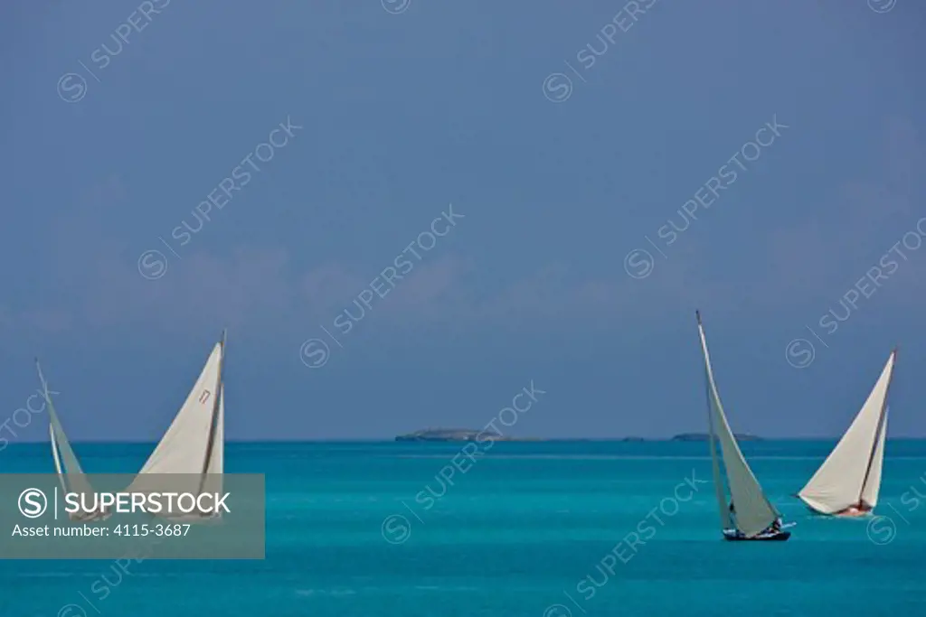 Four boats sailing on turquoise seas during the Bahamian Sloop regatta, Georgetown, Exumas, Bahamas. April 2009.
