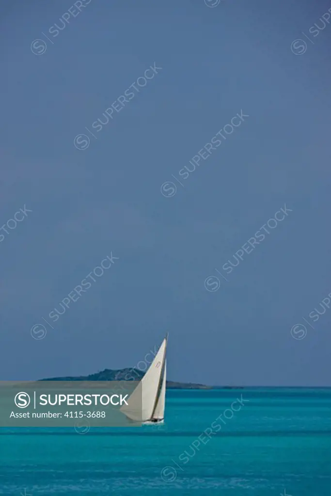 Lone boat sailing on turquoise seas during the Bahamian Sloop regatta, Georgetown, Exumas, Bahamas. April 2009.