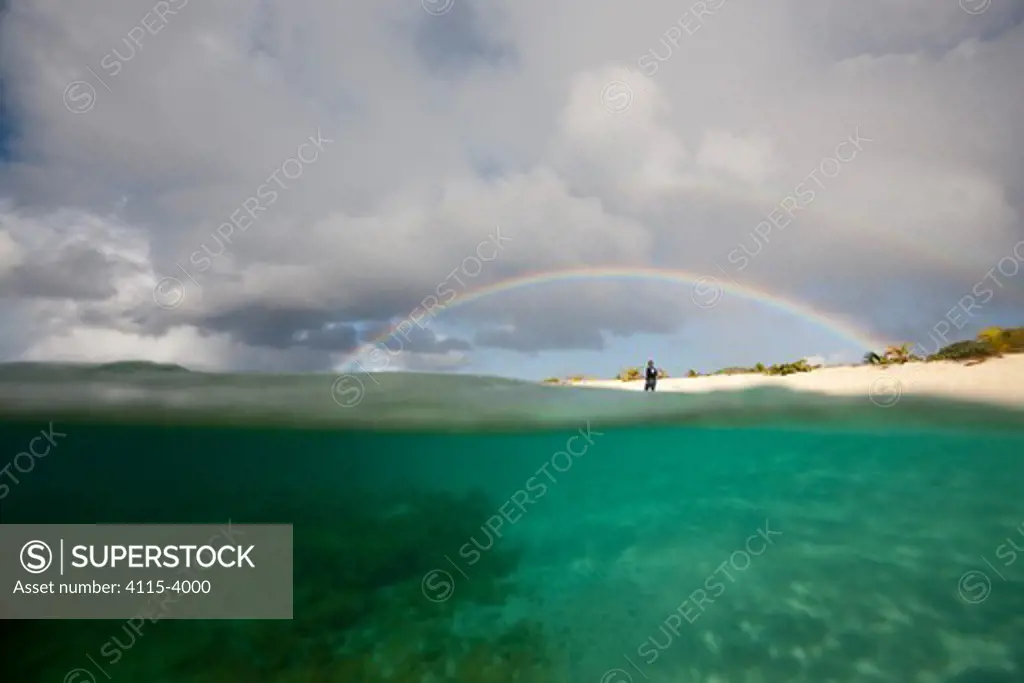 Figure beneath rainbow on Sandy Island, near Carriacou Island, the Grenadines, Caribbean, January 2010.