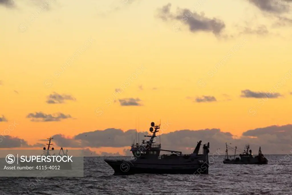 Fishing vessels at dusk on the North Sea, Europe, November 2010.