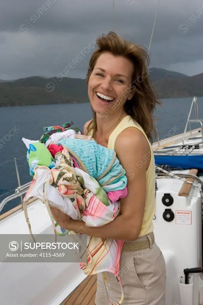 Woman carrying laundry aboard Sunsail Oceanis 523 in the BVI's. March 2006. Model and property released.