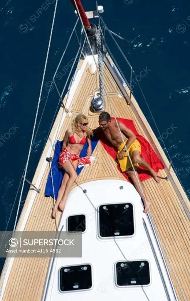 Couple relaxing on the foredeck of a Sunsail Oceanis 423 in the British Virgin Islands, March 2006. Model and property released.