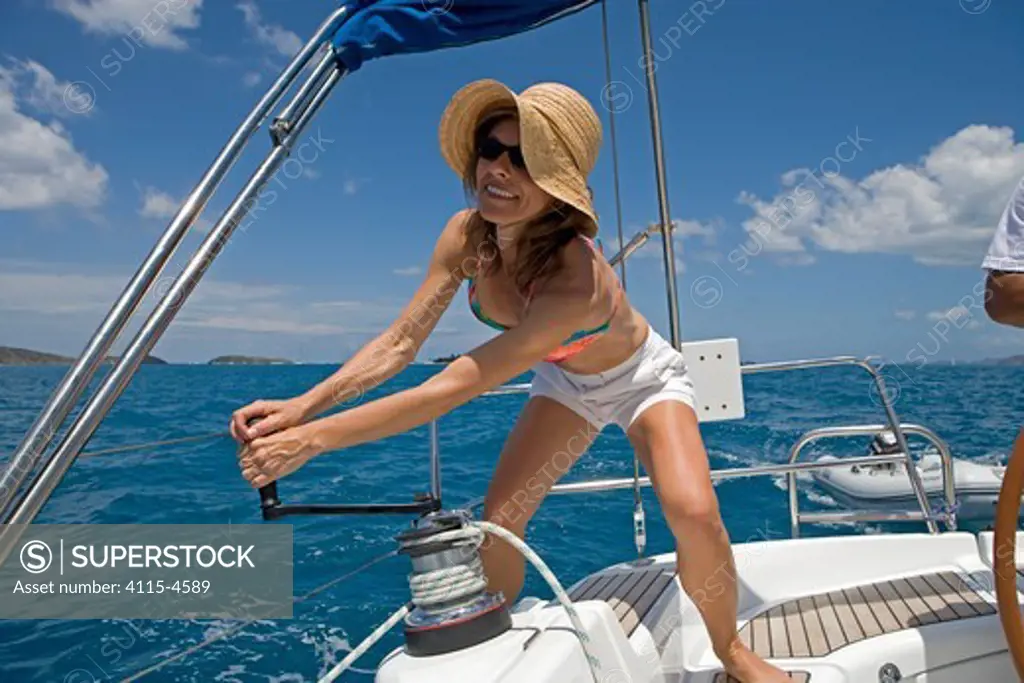 Woman winching aboard Sunsail Oceanis 423 in the BVI, March 2006. Model and property released.