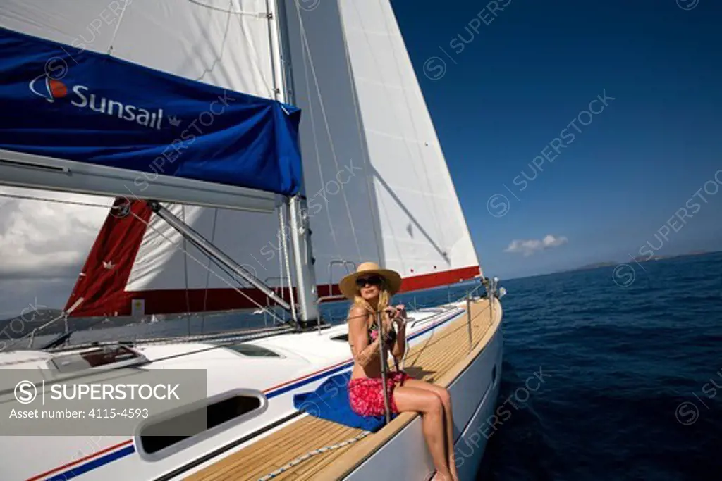 Woman relaxing on the rail of a Sunsail Oceanis 523 in the BVI, March 2006. Model and property released.