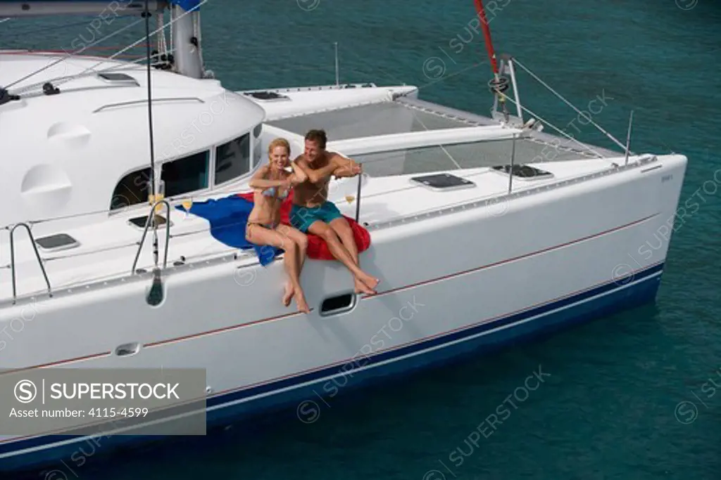 Couple relaxing on the rail of a Sunsail Lagoon 410 yacht in the BVI, April 2006. Model and property released.
