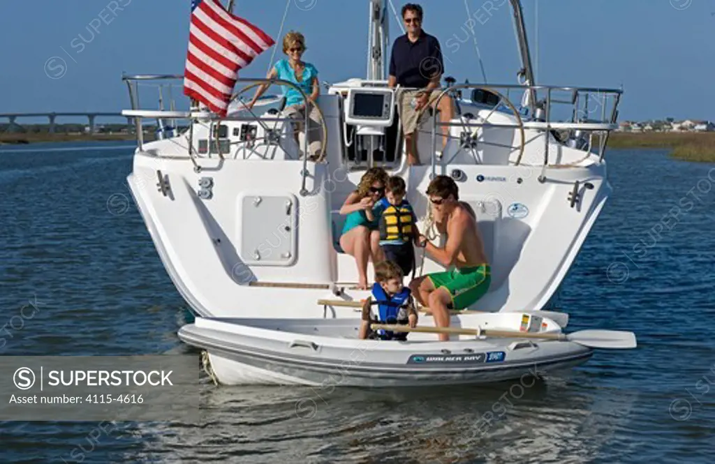 Adults helping children into a tender from the stern of a Hunter49 Off St. Augustine, Florida. April 2006, Model and property released.