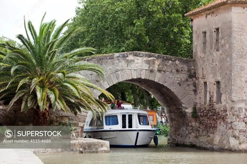 Boat passing under a bridge on the Canal Du Midi, Le Somail, France. July 2009. Model released.